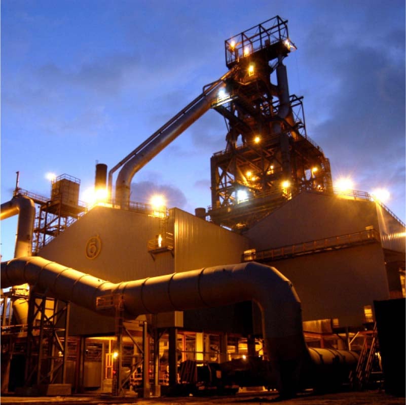 Illuminated industrial facility at dusk with large piping systems