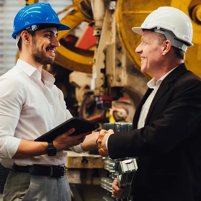 Lyden Oil representative and business executive wearing hard hats and shaking hands in industrial setting