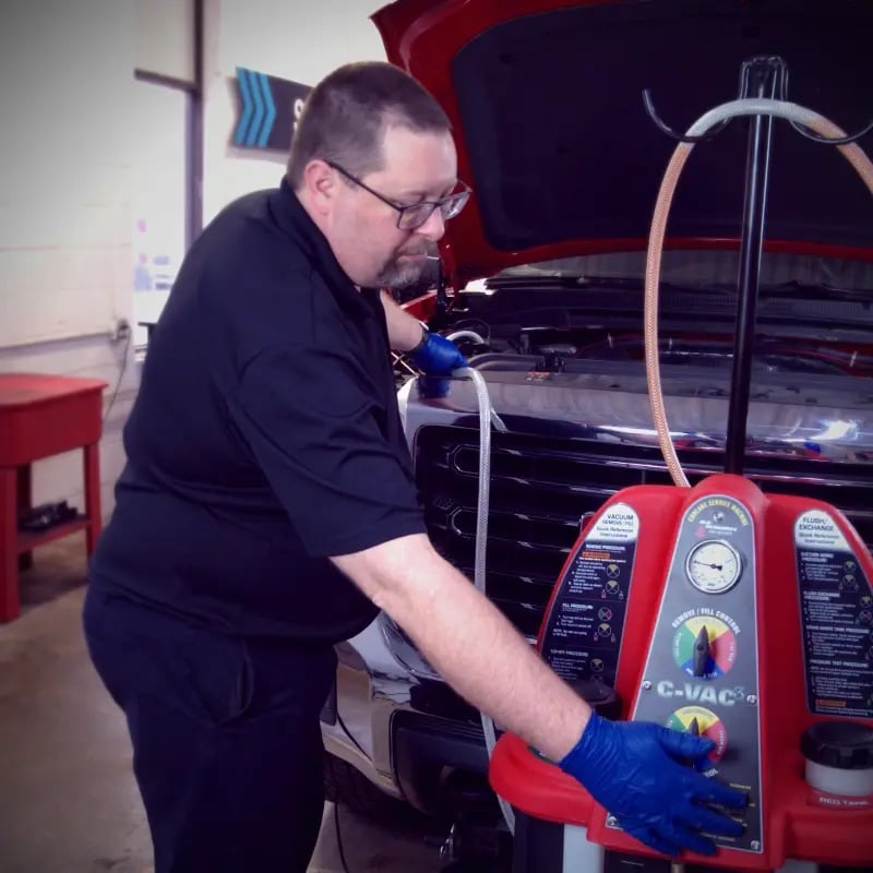 Auto technician using a C-VAC machine for fluid service on a vehicle